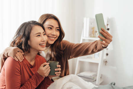 Young Asian Girls doing selfie on the bedの写真素材