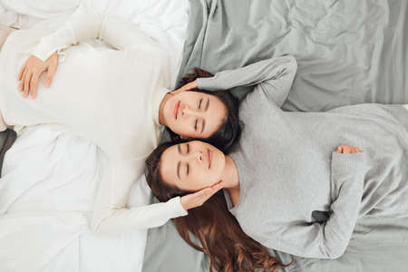 Overhead close up of young couple lesbian lying in bed together.の写真素材