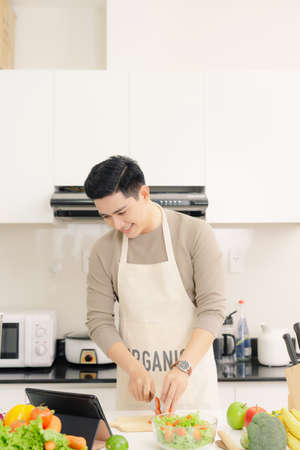 Handsome guy nice smile is cooking saladの写真素材