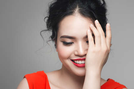 Glamorous stylish woman in evening make-up, covers half of her face with her palmの写真素材