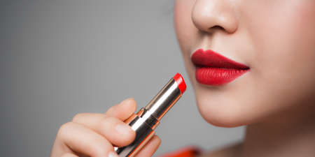 Beautiful young woman applying lipstickの写真素材