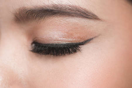 close-up portrait of young beautiful woman's closed, eye zone make up with black arrowの写真素材