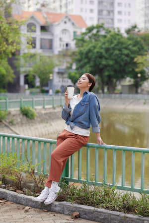 Girl fashion model hipster drinking coffee on the background of the cityの写真素材