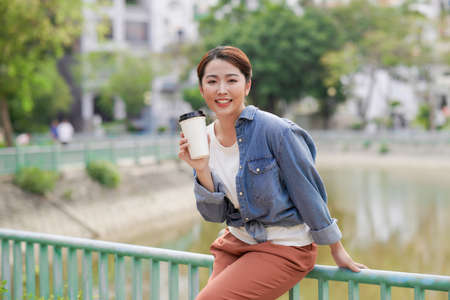 Girl fashion model hipster drinking coffee on the background of the cityの写真素材