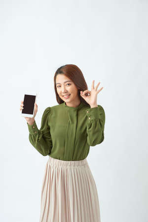 Satisfyer charming young woman hold smartphone and show okayの写真素材