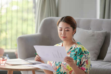 Happy self employed cheching paper files on a table at homeの写真素材