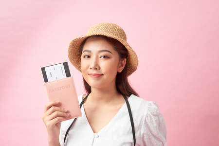 a happy young asian woman dressed in white dress and summer hat holding photo cameraの写真素材