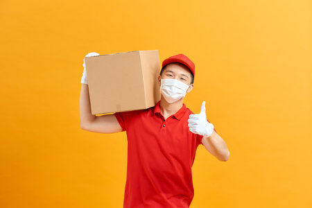 Courier in a face mask with a box in his hands.の写真素材