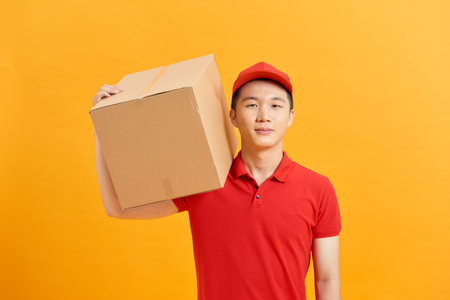 handsome young delivery man portrait isolated on yellowの写真素材