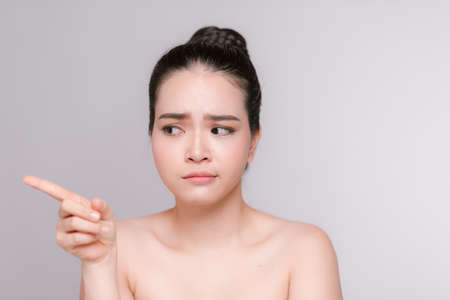 Gorgeous young asian woman pointing finger and looking to the side isolated on white backgroundの写真素材