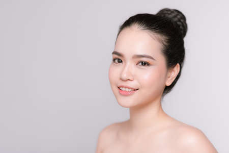 Beautiful young asian woman with clean fresh skin on gray backgroundの写真素材