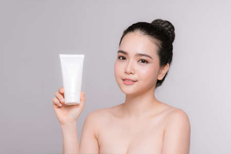Beautiful asian young woman face portrait holding and presenting cream tube productの写真素材