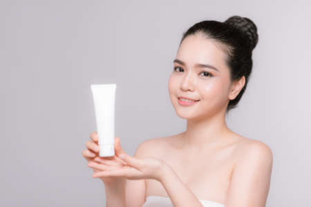 Beautiful asian young woman face portrait holding and presenting cream tube productの写真素材