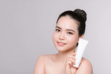 Beautiful asian Woman Face Portrait holding and presenting cream tube productの写真素材