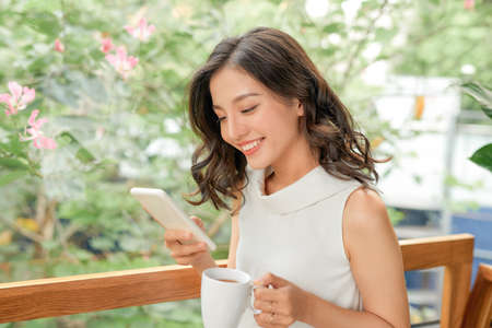 Happy casual beautiful woman is talking on a phone sitting on a sofa at home.の写真素材