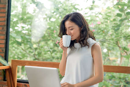 Happy pretty woman using laptop sitting on sofaの写真素材
