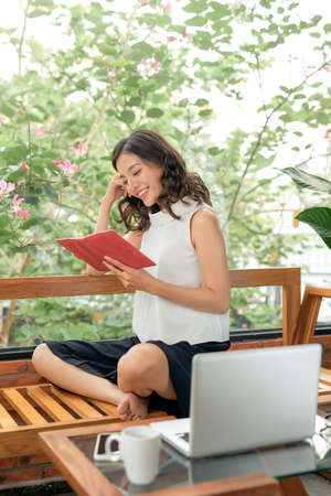 Woman reading diÌary on sofa at homeの写真素材