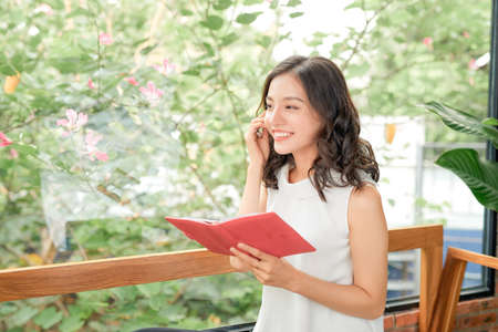 Smiling beautiful girl relaxing on a couch at home, using mobile phoneの写真素材