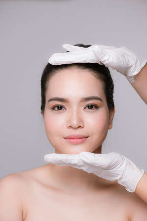 Closeup Of Beautician Hands In Gloves Touching Sexy Woman's Face.の写真素材