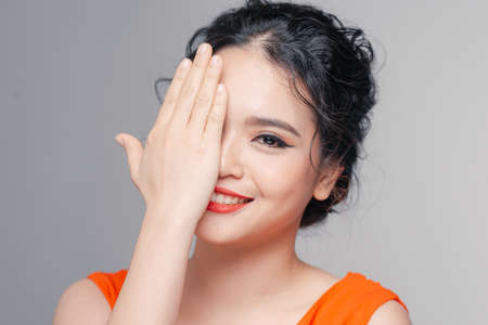 Attractive glamorous stylish woman in evening make-up, covers half of her face with her palmの写真素材