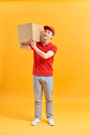 Portrait of a male delivery man holding a cargo box, backgroundの写真素材