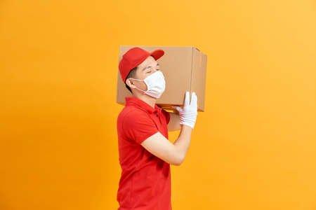 Courier in a face mask with a box in his hands.の写真素材