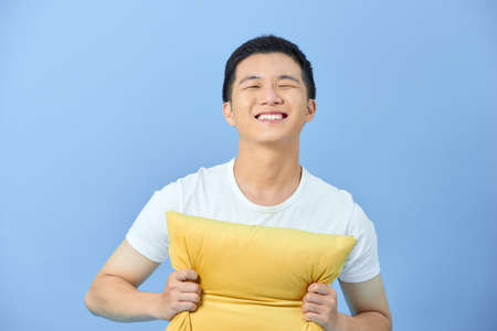 Man in home clothes hugging pillow with closed eyesの写真素材