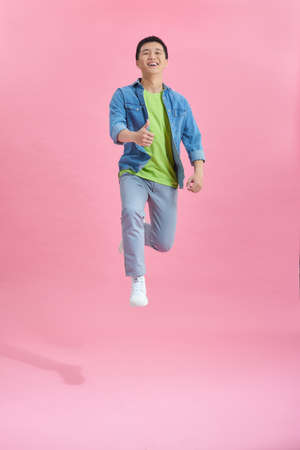 Handsome man jumping over pinkの写真素材