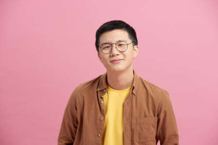 Asian man cheerful wearing glasses happy smile on pink backgroundの写真素材