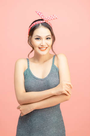 Beautiful young female with red lips with makeup wears retro headband over pink backgroundの写真素材