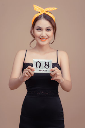 Beautiful young woman with calendar and figure 8 on pink background. International Women's Day celebrationの写真素材