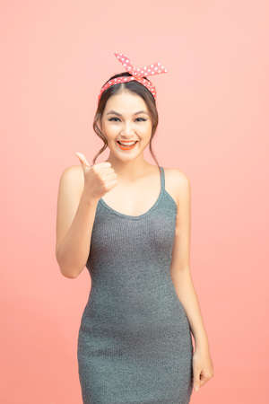 Pin up girl. Excited happy woman showing thumb up gesture or like sign.の写真素材
