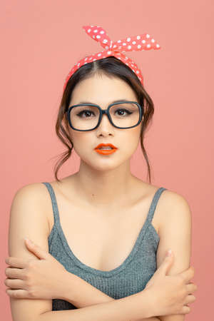 Beautiful young woman in pin-up image and bow on head, on pink backgroundの写真素材