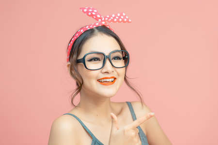 Young girl over isolated pink background pointing to the side to present a productの写真素材