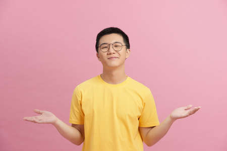 Portrait of uncertain doubtful guy hold hands blank space on pink backgroundの写真素材