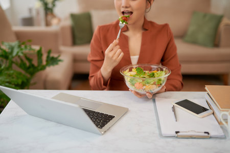 Woman has healthy business lunch in modern office interior.の写真素材