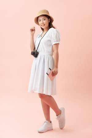 Fun travel portrait of smiling young beautiful Asian tourist woman holding passport isolated on pink backgroundの写真素材