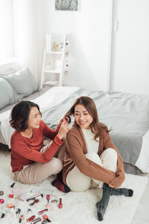 Young beautiful Asian couple love friend woman do hair on bed in bedroom.の写真素材