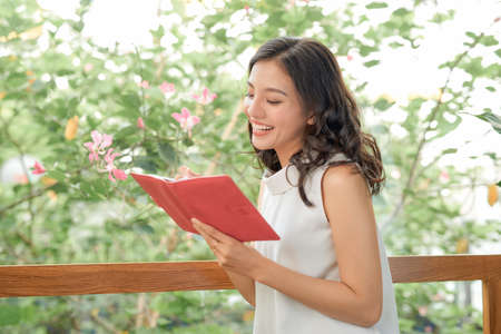Portrait of young beautiful asian woman relax holding book in coffee shop with copy spaceの写真素材