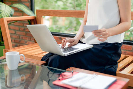 female relax feeling happy online shopping sitting on sofa in living room at homeの写真素材