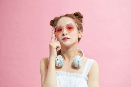 Photo of young excited  girl happy positive smile hands touch sunglass isolated over pink color backgroundの写真素材