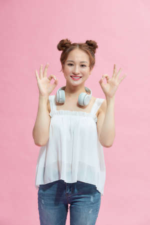Cute woman with okay hand gesture isolated on pink background.の写真素材