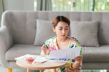 young woman spending in living room sitting at floor doing paperworkの写真素材