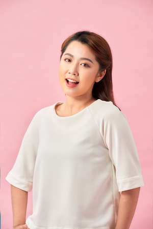 Natural young woman with happy smile, standing against pink backgroundの写真素材