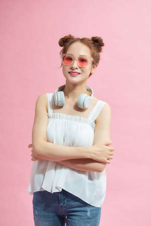 Portrait of a serious asian woman with arms folded standing over pink backgroundの写真素材