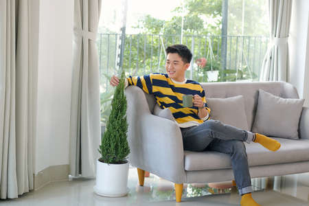 young man hold cup of coffee think relaxing sitting on couch,の写真素材