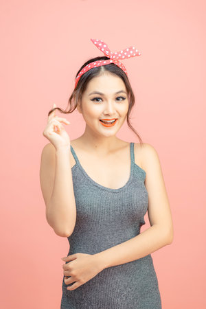 Young girl posing over pink wall, looking at camera.の写真素材