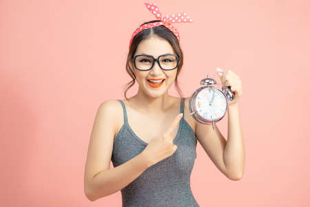 Young pretty woman over isolated background holding vintage alarm clockの写真素材