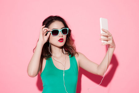 The beautiful Asian woman is using electricity while listening to music with white wireless headphonesの写真素材