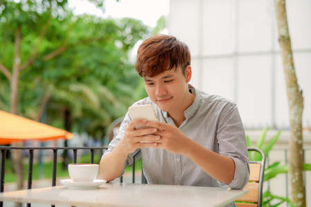 Young man reading information on smartphone when working in cafeの写真素材